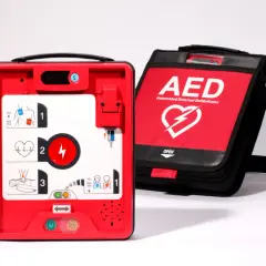 Czerwony defibrylator AED i jego czarna torba transportowa na białym tle.