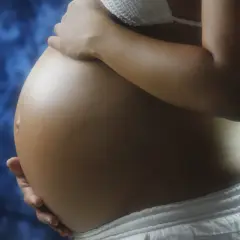 Brzuch ciężarnej kobiety, delikatnie dotykany dłońmi. Warto pamiętać o konsultacji z lekarzem w sprawie stosowania leków, np. ibuprom w ciąży.