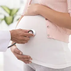 Lekarz osłuchuje brzuch ciężarnej stetoskopem. Stan przedrzucawkowy w ciąży jest monitorowany.