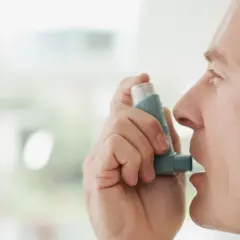 Mężczyzna używa inhalatora Miflonide Breezhaler, aby złagodzić objawy astmy.