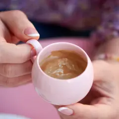 Delikatna kawa w różowej filiżance, trzymana w dłoniach z francuskim manicure. Chwila relaksu, nawet w ciąży.