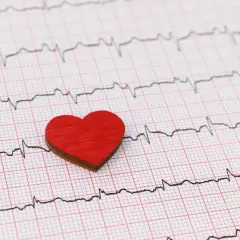 Czerwone serce na tle zapisu EKG. Zwróć uwagę na subtelne zmiany, które mogą sygnalizować cichy zawał objawy.