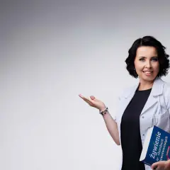 Dietetyczka kliniczna z książką o żywieniu w chorobach nowotworowych, gestem zaprasza do rozmowy.