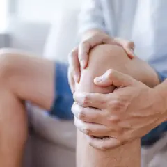 Mężczyzna trzyma się za bolące kolano, sugerując uraz kolana, który może być klasyfikowany według ICD 10.