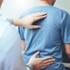 Fizjoterapeuta bada plecy pacjenta, sprawdzając, jak długo trwa ból.