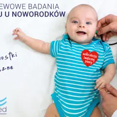 Uśmiechnięty noworodek podczas badań przesiewowych słuchu. Lekarz wykonuje badanie aparaturą.