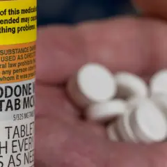 Oxycodone co to za lek? Na zdjęciu widać butelkę z lekiem i garść białych tabletek.