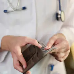 Lekarz w białym kitlu z weterynarzem wyciąga pieniądze z portfela. Ile zarabia neurolog?