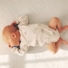 Malutkie dziecko śpi w łóżeczku, otulone kołderką. Smoczek w buzi, spokojny sen.