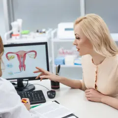 Lekarka omawia z pacjentką budowę macicy i potencjalne problemy, takie jak atonia macicy, wskazując na ekranie.
