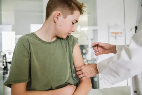 Chłopiec otrzymuje szczepienie HPV. Lekarz podaje zastrzyk, a rodzice martwią się o ewentualne szczepienie hpv skutki uboczne.