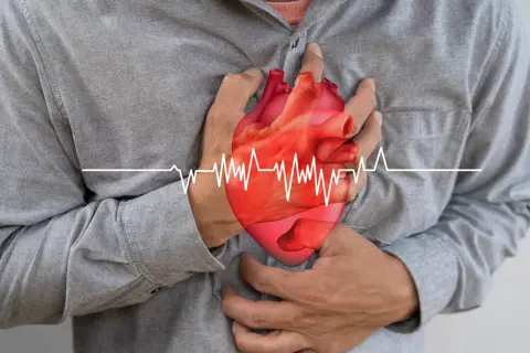 Mężczyzna trzyma się za serce, na którym widnieje wykres EKG. Może to symbolizować problemy z sercem, które leczy się m.in. lekiem Dilzem.