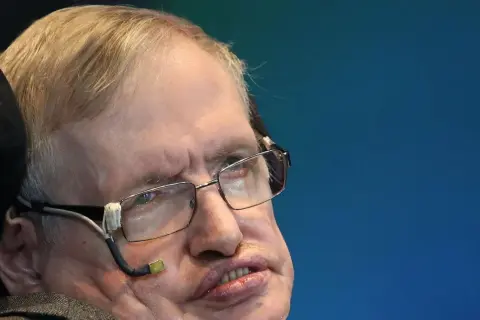 Stephen Hawking, mimo swojej choroby, z okularami i aparaturą do komunikacji, patrzy w dal.