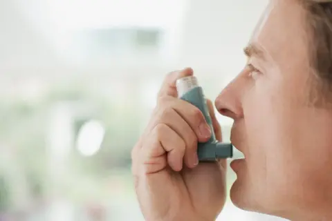 Mężczyzna używa inhalatora Miflonide Breezhaler, aby złagodzić objawy astmy.