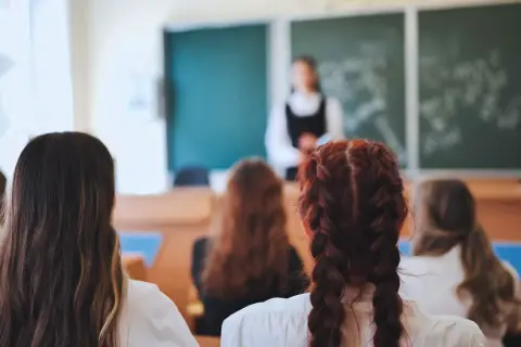 Uczniowie słuchają lekcji o edukacji zdrowotnej. Nauczycielka stoi przed tablicą, a dzieci siedzą w ławkach, skupione na przekazywanej wiedzy.