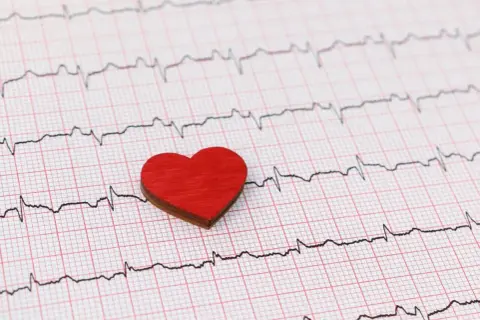 Czerwone serce na tle zapisu EKG. Zwróć uwagę na subtelne zmiany, które mogą sygnalizować cichy zawał objawy.