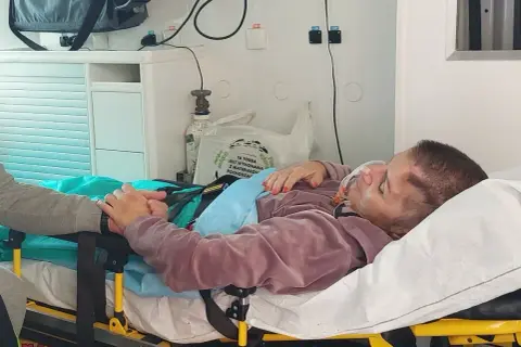 Pacjentka po pęknięciu tętniaka mózgu, z maską tlenową, trzymająca się bliskiej osoby. Rokowania niepewne.