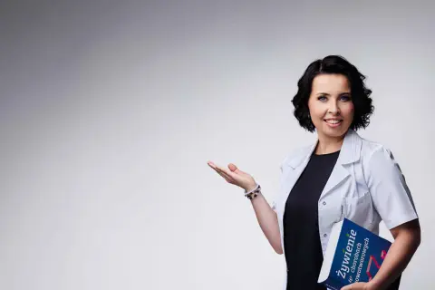 Dietetyczka kliniczna z książką o żywieniu w chorobach nowotworowych, gestem zaprasza do rozmowy.