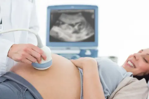 Radość przyszłej mamy podczas badania USG. Lekarz wykonuje badanie USG, monitorując rozwój dziecka. To ważny element opieki w perinatologii.