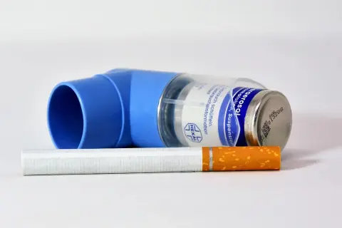 Niebieski inhalator Ultibro i papieros na białym tle.