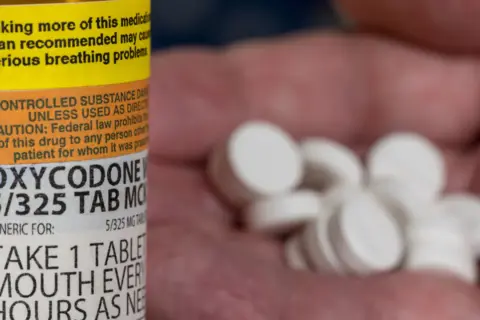 Oxycodone co to za lek? Na zdjęciu widać butelkę z lekiem i garść białych tabletek.