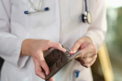Lekarz w białym kitlu z weterynarzem wyciąga pieniądze z portfela. Ile zarabia neurolog?