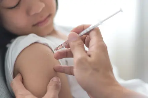 Dziecko otrzymuje szczepienie przeciwko polio. Lekarz podaje zastrzyk, chroniąc przed tą groźną chorobą.