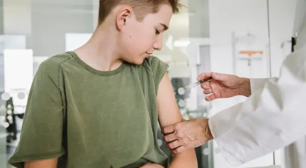 Chłopiec otrzymuje szczepienie HPV. Lekarz podaje zastrzyk, a rodzice martwią się o ewentualne szczepienie hpv skutki uboczne.