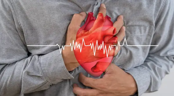 Mężczyzna trzyma się za serce, na którym widnieje wykres EKG. Może to symbolizować problemy z sercem, które leczy się m.in. lekiem Dilzem.