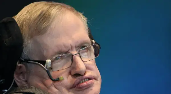 Stephen Hawking, mimo swojej choroby, z okularami i aparaturą do komunikacji, patrzy w dal.