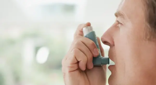 Mężczyzna używa inhalatora Miflonide Breezhaler, aby złagodzić objawy astmy.