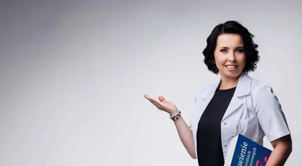 Dietetyczka kliniczna z książką o żywieniu w chorobach nowotworowych, gestem zaprasza do rozmowy.