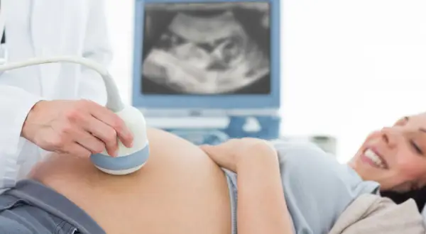 Radość przyszłej mamy podczas badania USG. Lekarz wykonuje badanie USG, monitorując rozwój dziecka. To ważny element opieki w perinatologii.