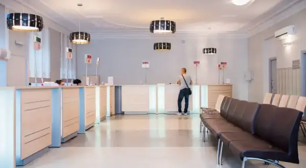 Recepcja w nowoczesnej klinice medycznej z poczekalnią i systemem kolejkowym.