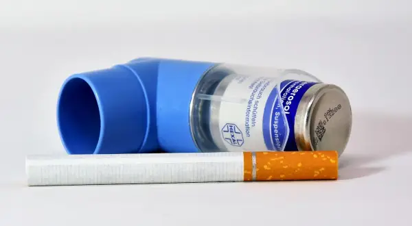 Niebieski inhalator Ultibro i papieros na białym tle.