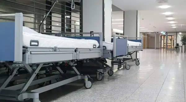 Puste łóżka szpitalne w korytarzu. Zastanawiasz się, ile zarabia salowa w szpitalu?