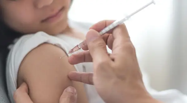 Dziecko otrzymuje szczepienie przeciwko polio. Lekarz podaje zastrzyk, chroniąc przed tą groźną chorobą.