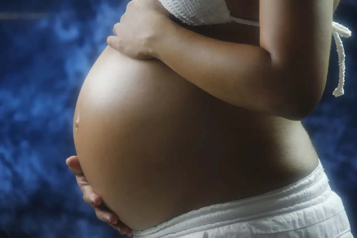Brzuch ciężarnej kobiety, delikatnie dotykany dłońmi. Warto pamiętać o konsultacji z lekarzem w sprawie stosowania leków, np. ibuprom w ciąży.