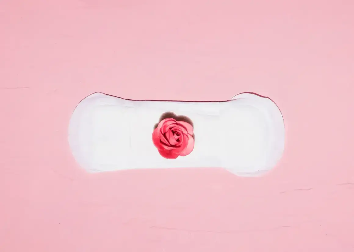 Delikatne krwawienie implantacyjne, symbolizujące nowy początek, na tle różowej tekstury.