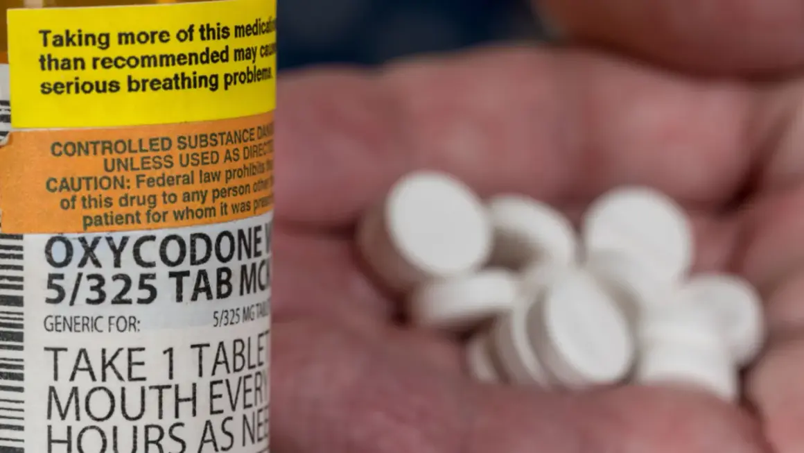 Oxycodone co to za lek? Na zdjęciu widać butelkę z lekiem i garść białych tabletek.
