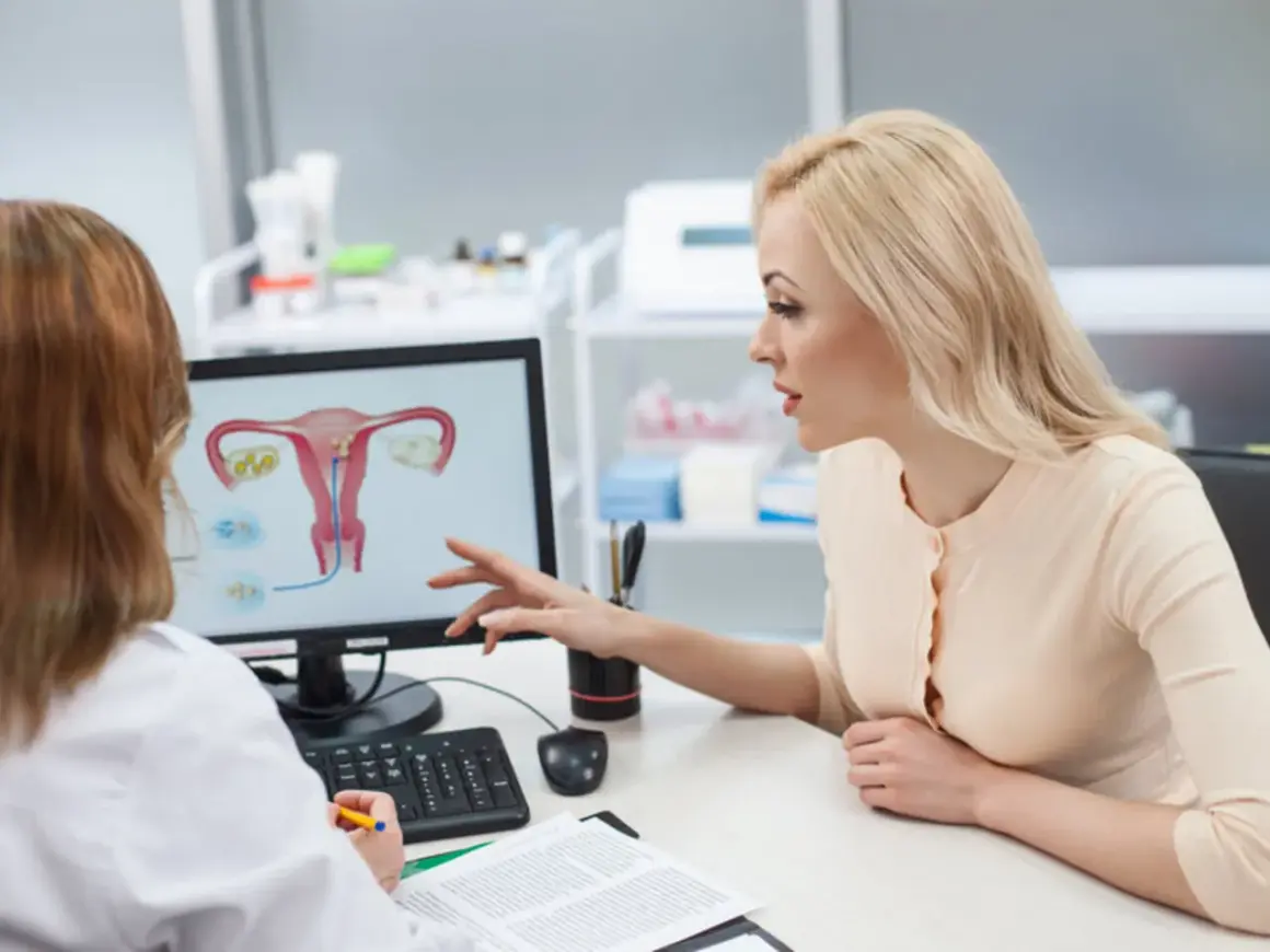 Lekarka omawia z pacjentką budowę macicy i potencjalne problemy, takie jak atonia macicy, wskazując na ekranie.