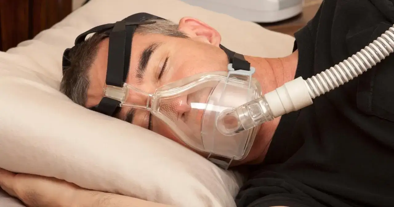 Mężczyzna śpi z maską CPAP, która pomaga mu oddychać. Czy to jego klątwa Ondyny?