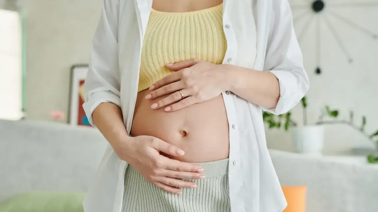 Kobieta w ciąży delikatnie obejmuje brzuszek. Warto pamiętać o bezpieczeństwie i konsultować każdy lek, nawet ibuprom w ciąży, z lekarzem.