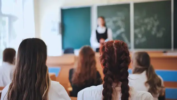 Uczniowie słuchają lekcji o edukacji zdrowotnej. Nauczycielka stoi przed tablicą, a dzieci siedzą w ławkach, skupione na przekazywanej wiedzy.