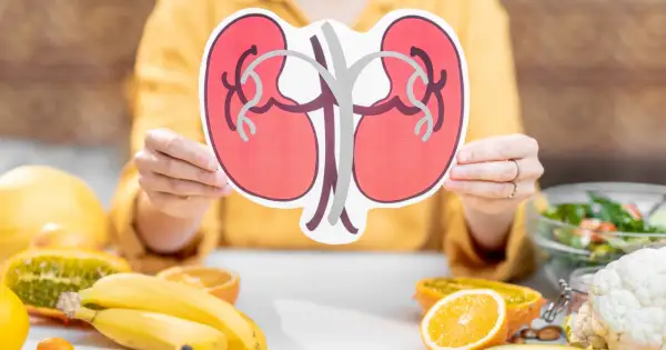 Osoba trzyma symbol nerek, a na stole leżą owoce i warzywa. Zastanawiasz się, co pić na chore nerki? Woda i zdrowe napoje to podstawa.