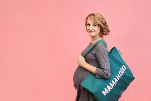 Przyszła mama z torbą "Mamahood" gotowa do szpitala. Sprawdź, co zabrać do szpitala, by niczego nie zapomnieć.